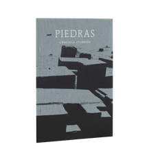 Afbeelding in Gallery-weergave laden, Boekcover Graciela Iturbide - Piedras. grijze linnen cover waarop en schaduwen zijn gezeefdrukt in het zwart. Witte titeltekst. 