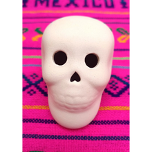 Afbeelding in Gallery-weergave laden, Witte onbeschilderde keramische schedel, vooraanzicht, op een roze Mexicaanse doek